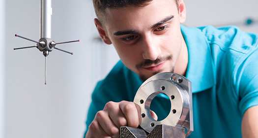 INDEX Zerspanungsmechaniker Azubi schaut sich ein Werkstück an